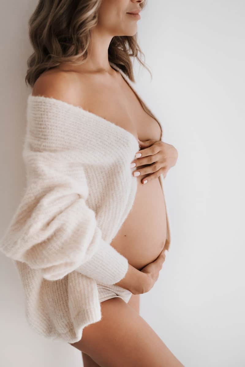 Schwangere mit Strickjacke und nackigem Babybauch