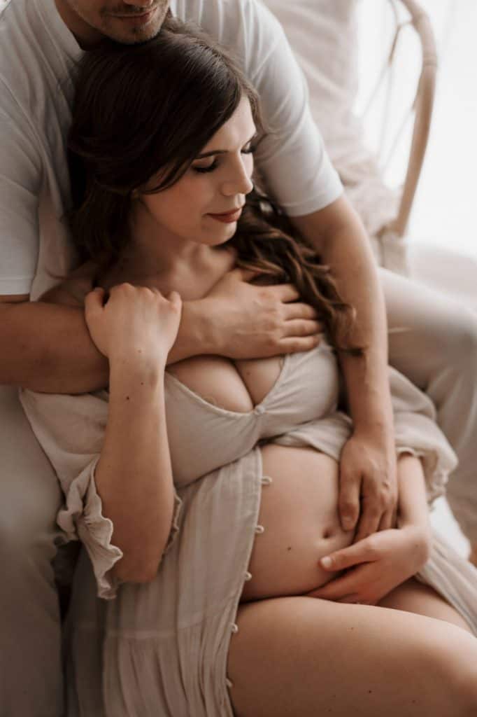 Schwangere wird lehnt an ihren Partner der sie umarmt